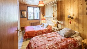A wooden cabin room with two beds, a window, a mirror, and a wall-mounted lamp. - Spacious apartment, pets allowed - 8 guests (Valloire)