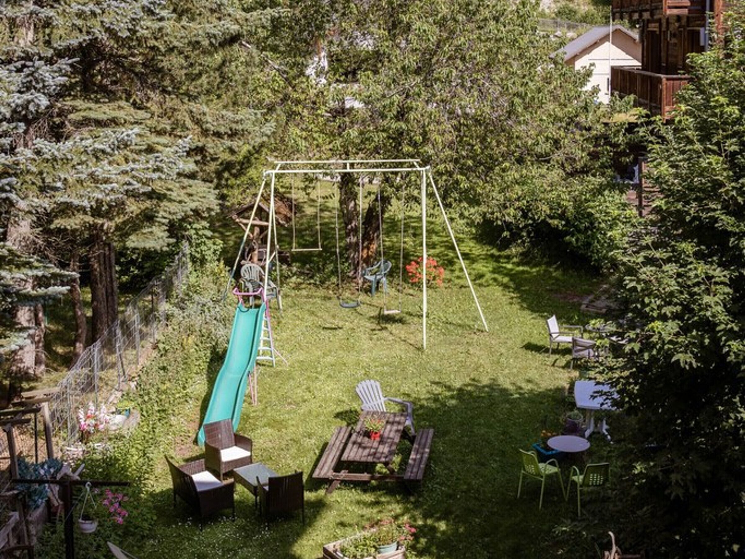 A backyard with a swing set, a slide, and outdoor furniture.