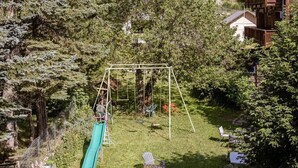 A backyard with a swing set, a slide, and outdoor furniture. - Spacious apartment, pets allowed - 8 guests (Valloire)