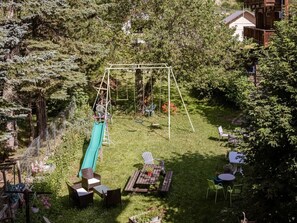 Ein Garten mit Schaukel, Rutsche und Gartenmöbeln.