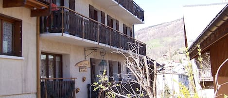 A multi-story building with balconies, a sign indicating a restaurant, and a view of a mountainous landscape.