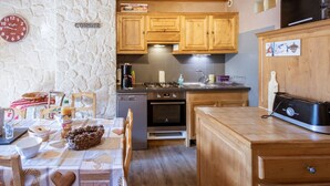 A compact kitchen with wooden cabinets, a stove, and a coffee machine. - Spacious apartment, pets allowed - 8 guests (Valloire)