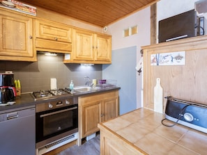 A kitchen with wooden cabinets, a gas stove, a dishwasher, and a refrigerator. - Spacious apartment, pets allowed - 8 guests (Valloire)