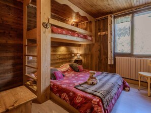 A cozy room with a bunk bed, a bedside table, a chair, and a window with a view. - Spacious apartment, pets allowed - 8 guests (Valloire)