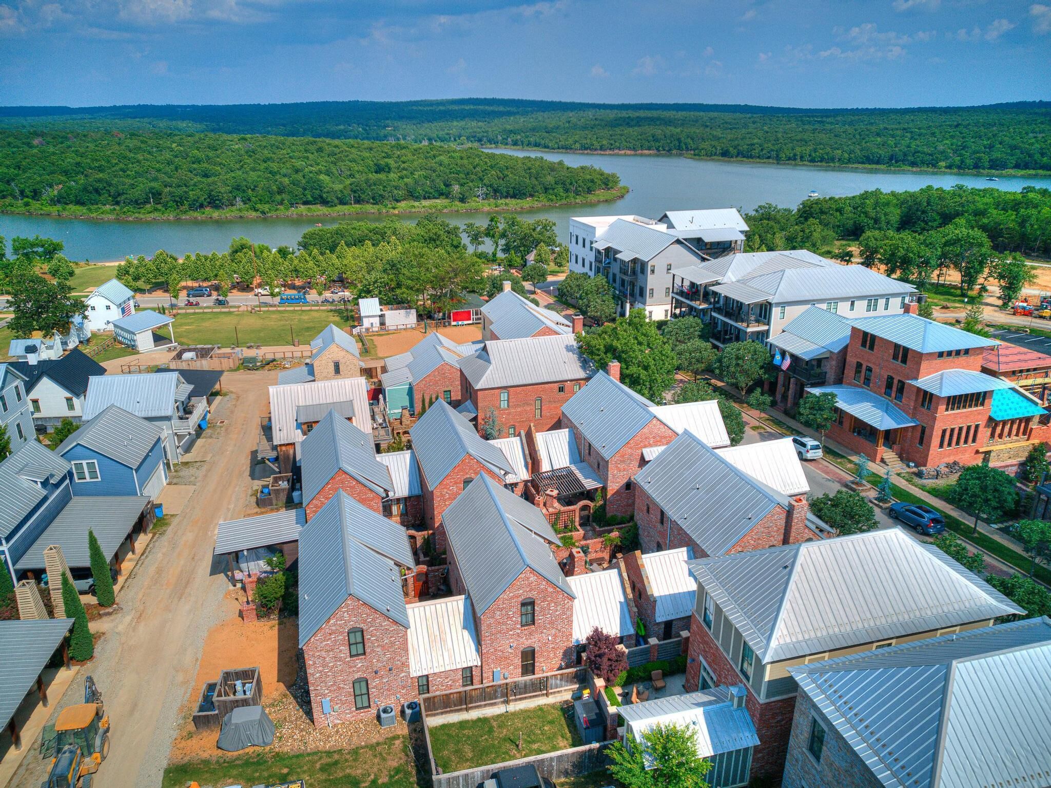 An aerial view of a residential area with houses, a road, and a river in the background.