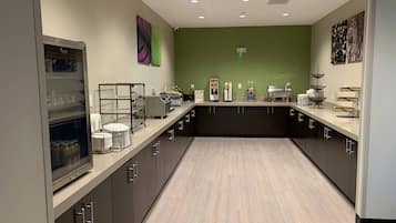 A modern kitchen with dark cabinets, a light countertop, and a green accent wall.