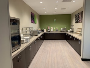 A modern kitchen with dark cabinets, a light countertop, and a green accent wall. - Sleep Inn North - Central York (York)