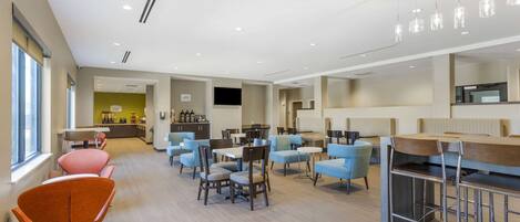 A modern hotel lobby with multiple seating areas, including a bar and a dining area.