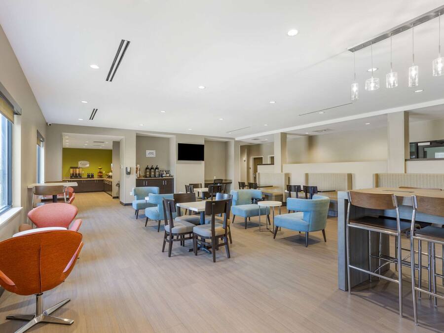 Un hall d’hôtel moderne doté de plusieurs espaces de détente, notamment un bar et un coin repas.