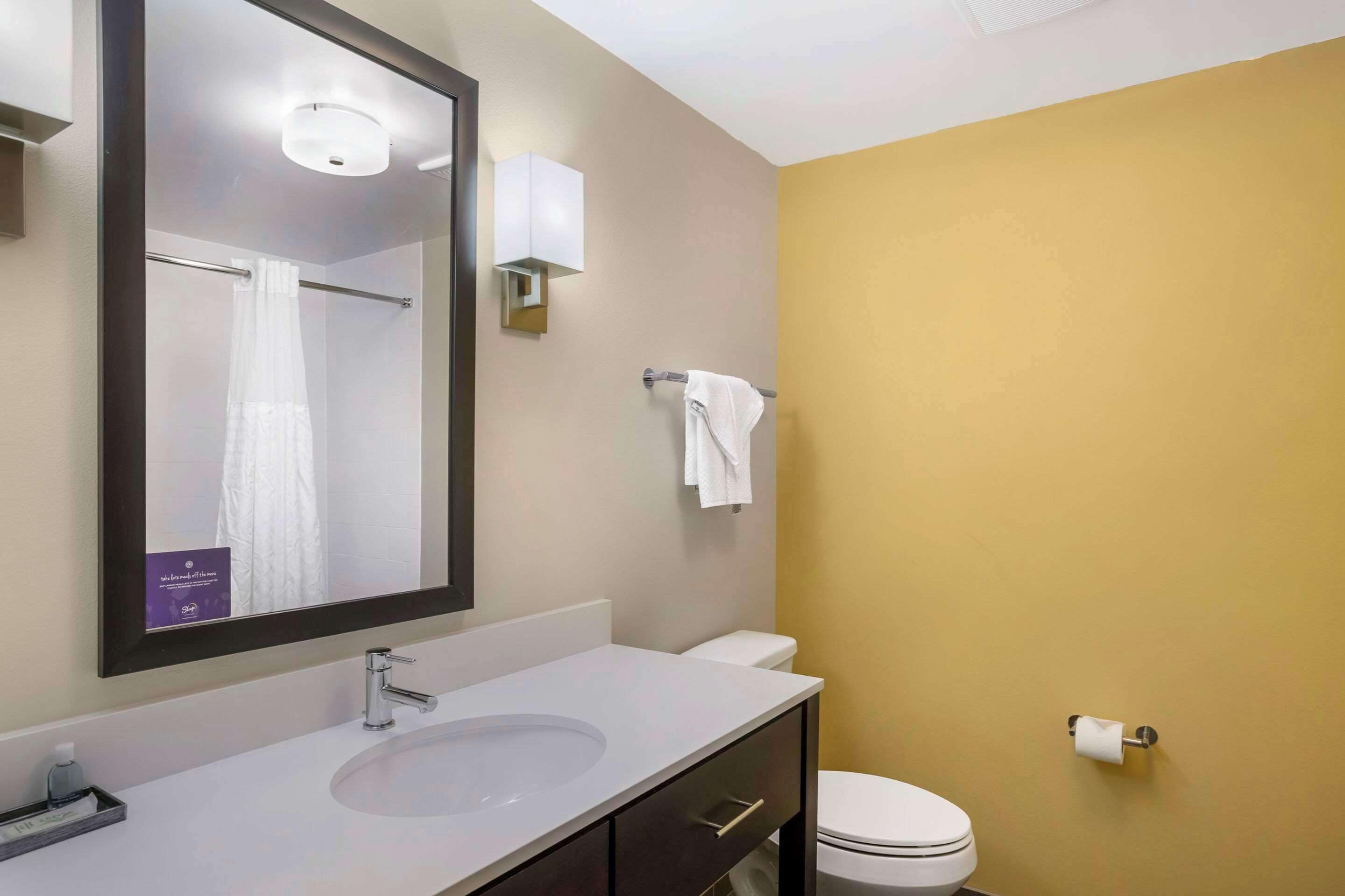 Une salle de bain avec un lavabo blanc, un miroir, un porte-serviettes et des toilettes.