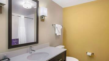Une salle de bain avec un lavabo blanc, un miroir, un porte-serviettes et des toilettes.