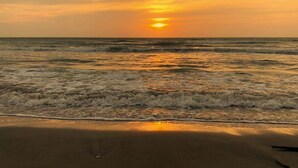 Ein Strand mit Wellen und einem Sonnenuntergang.