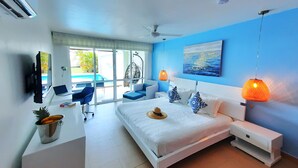Ein modernes Schlafzimmer mit Bett, Nachttischen, einem Schreibtisch mit Laptop, einem Hängesessel und Blick auf einen Swimmingpool.