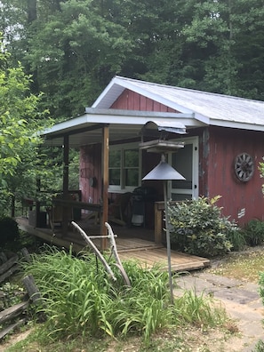 Escape to a secluded cabin surrounded by lush greenery, featuring a cozy covered porch and simple design.