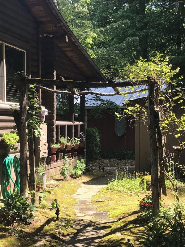 Step into a serene retreat surrounded by lush gardens and a covered porch with potted plants.