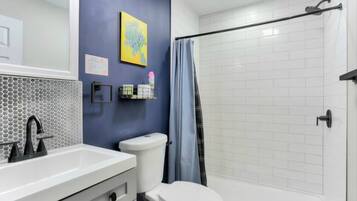 Une salle de bain avec un lavabo blanc, des toilettes et un espace douche.