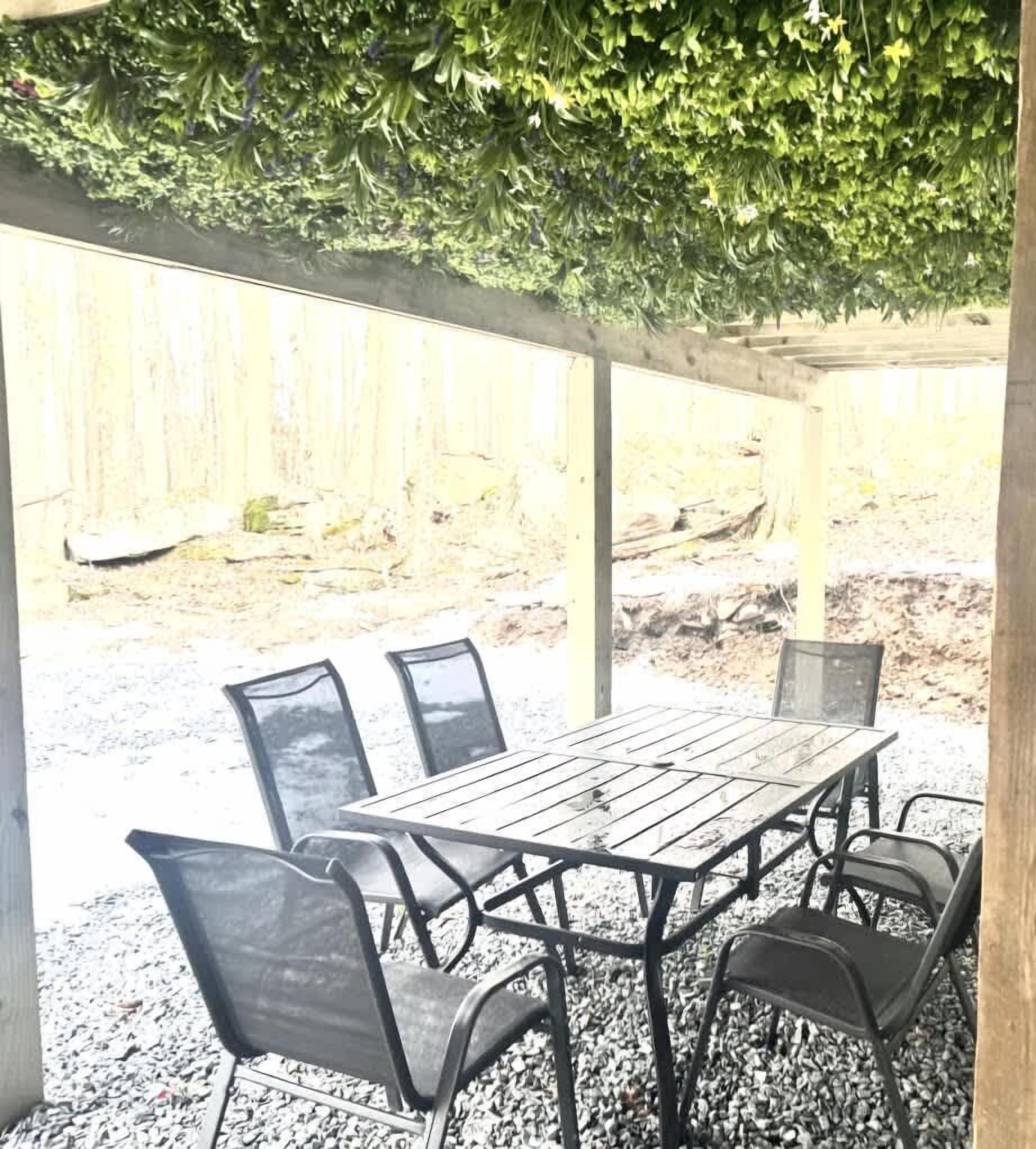 Un patio al aire libre con una mesa de madera y cuatro sillas.
