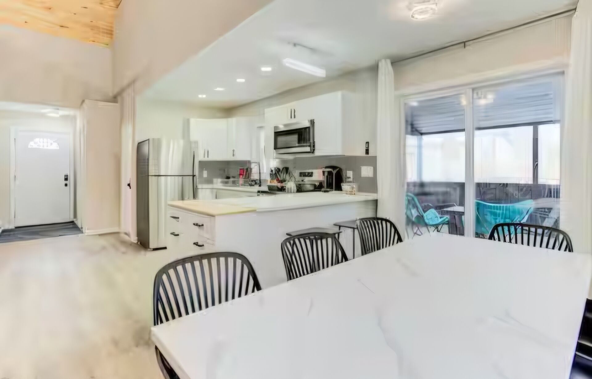 A modern kitchen with a central island, dining table, and chairs.