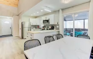 A modern kitchen with a central island, dining table, and chairs.