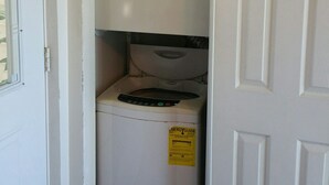 Une petite buanderie équipée d’un lave-linge à chargement frontal et d’un sèche-linge.