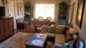 Un salon comprenant un canapé, une table basse, un téléviseur, un meuble en bois et un coin repas avec des chaises et une table.
