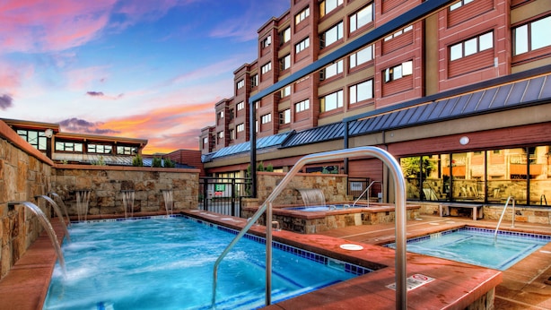 Un hotel con zona de piscina que incluye varios jacuzzis y una pared de piedra.