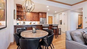 A modern kitchen with wooden cabinets, a stainless steel refrigerator, and a round dining table with chairs.