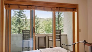 A bedroom with a large sliding glass door leading to a balcony with two chairs and a table.