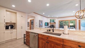 A modern kitchen with a large island, stainless steel appliances, and a view to the dining area.