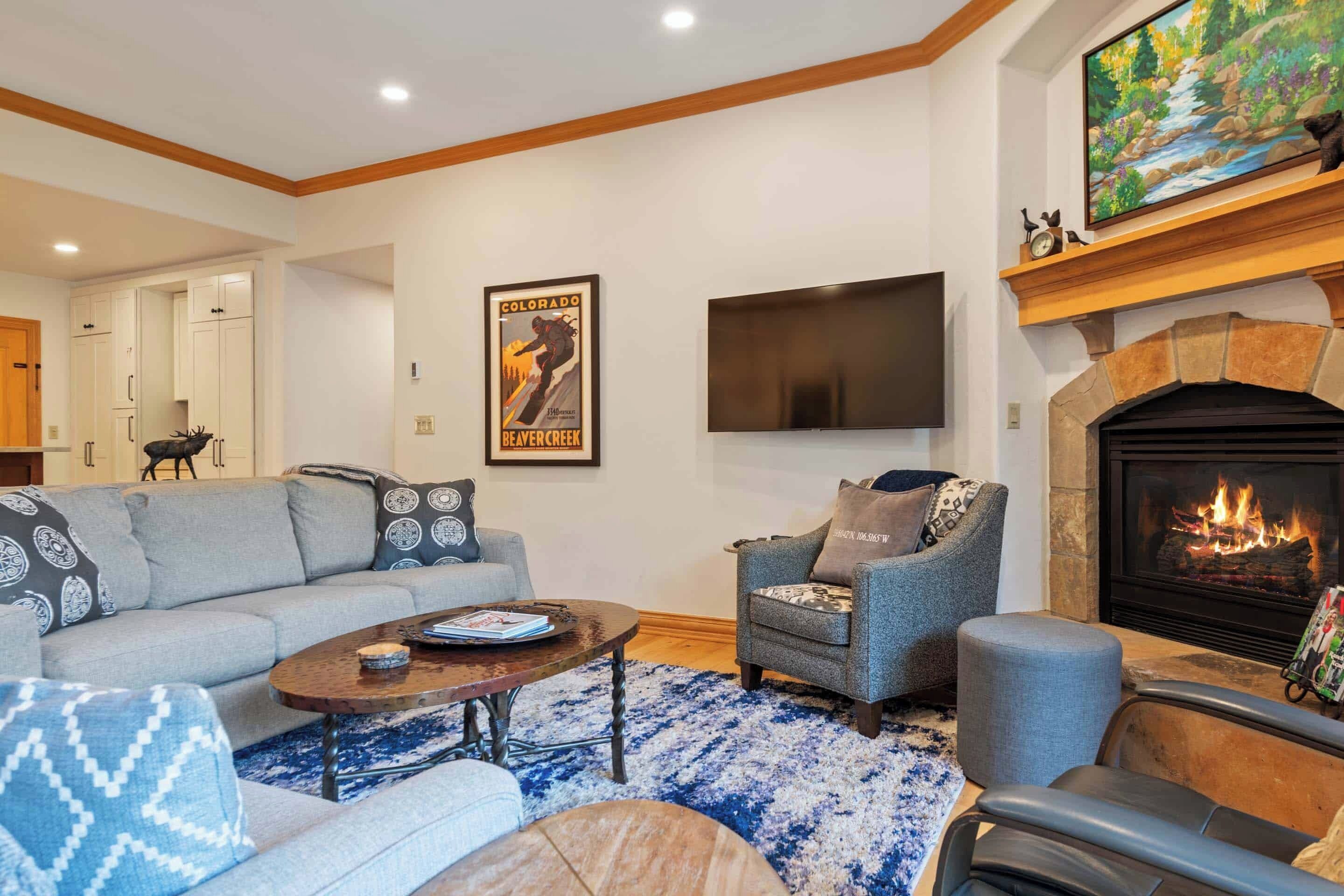 A living room with a fireplace, a mounted TV, and a poster on the wall.