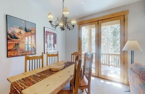 A dining area with a wooden table and chairs, a chandelier, and two framed artworks on the wall. - Charming Condo Nestled in the East Keystone Resort Neighborhood, Shuttle to Ski Slopes, Outdoor Pool and Hot Tub (Keystone)