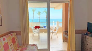 Una habitación con cama, una mesa y vista al mar por una puerta corrediza.