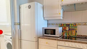 A kitchen with a washing machine, a refrigerator, a microwave, and a stove. - Las Vegas 3000 (Peniscola)