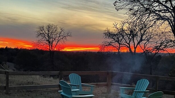 Eine Terrasse mit zwei Adirondack-Stühlen und einem Feuerkorb.