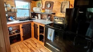 Eine kleine Küche mit Holzausstattung, einem Edelstahlkühlschrank und einem integrierten Backofen.