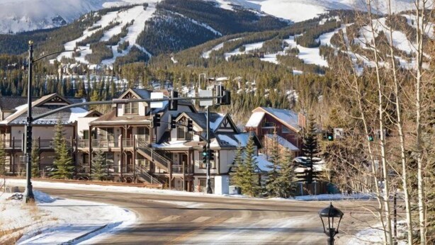 A ski resort with traditional wooden buildings, a clear view of snow-covered mountains, and a road leading into the scene. - 3 Bedroom Townhome in Downtown Breckenridge, off Main Street With Pool, and Hot Tubs (Breckenridge)