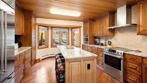 A kitchen with wooden cabinets, a central island, and a large oven. - Luxury Ski in, Ski out 2 Bedroom Colorado Vacation Rental Steps From the Ski Slopes With Hot Tub and Pool (Snowmass Village)
