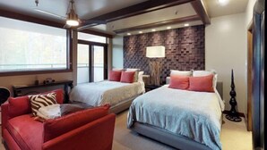 Ett modernt hotellrum med två sängar, en röd soffa, ett stort fönster och en dekorativ vägg.