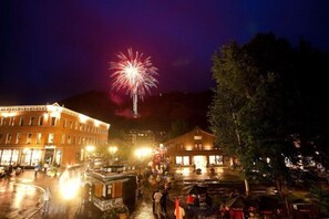 A nighttime scene with a building, a fountain, and a crowd. - Downtown 2 Bedroom Mountain Vacation Rental in the Heart of Downtown Aspen One Block From Silver Queen Gondola (Aspen)