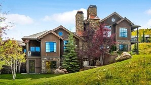 A two-story house with a stone facade, large windows, and a sloped roof.