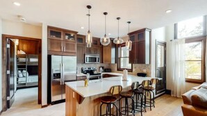 A modern kitchen with a central island, bar stools, and pendant lighting. - Premier Ski in, Ski-out 2 Bedroom Condo With Spectacular Views, Heated Outdoor Pool and Hot Tub, Short Walk to Village (Snowmass Village)