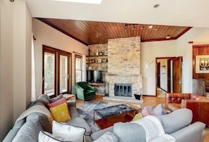 A spacious living room with a stone fireplace, a green armchair, and a leather sofa.