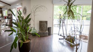Una habitación con piso de madera, una estatua de Buda y un ventanal con vistas a la vegetación.