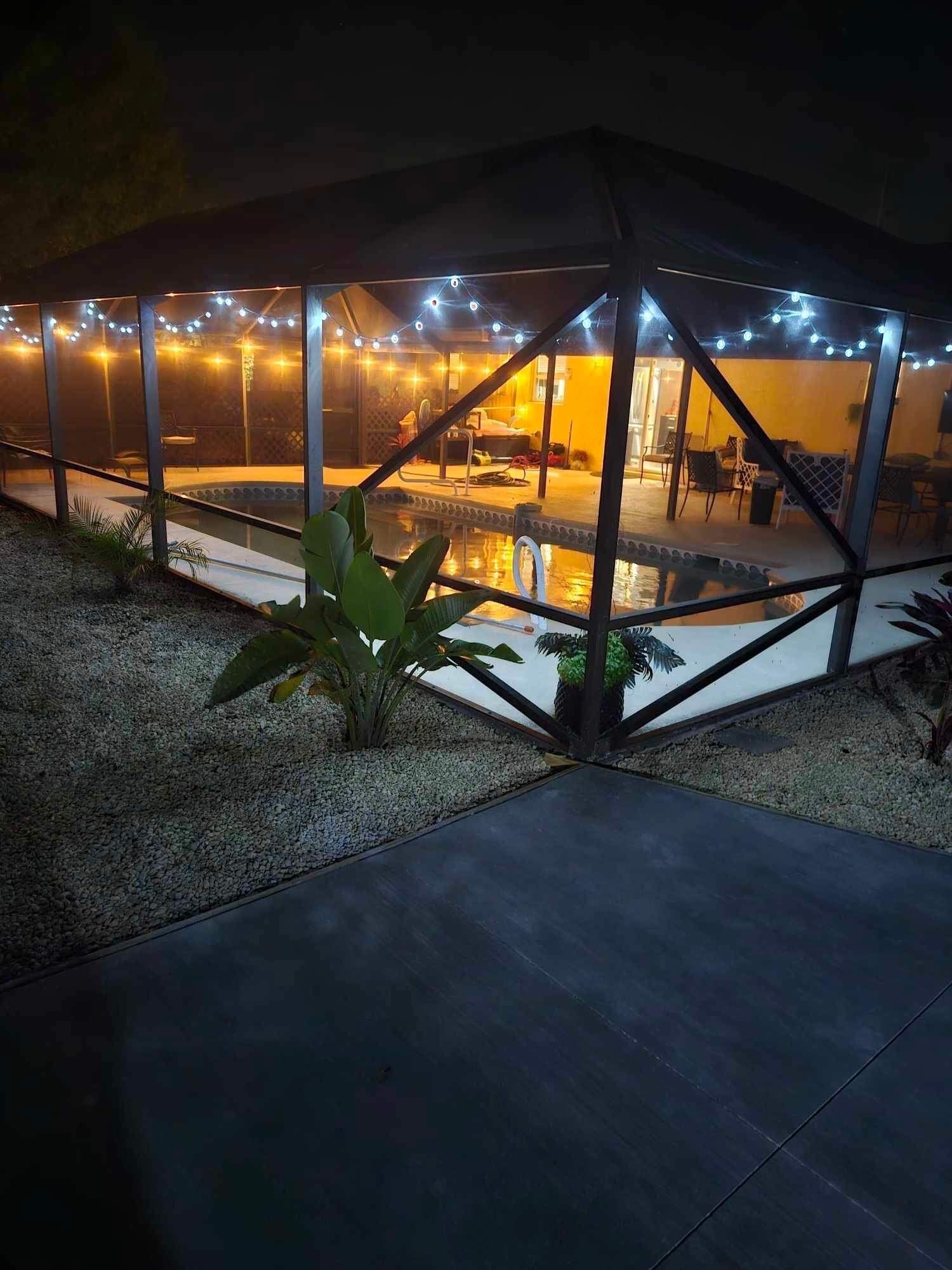 A covered outdoor area with a pool, string lights, and seating.