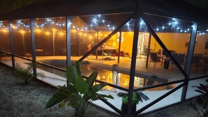 Ein überdachter Außenbereich mit Pool, Lichterketten und Sitzgelegenheiten.
