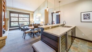 A modern kitchen with a large island, built-in appliances, and a dining area with chairs and a table.
