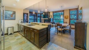 A modern kitchen with a large island, dark cabinetry, and pendant lighting.