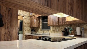 A modern kitchen with wooden cabinetry, a marble countertop, and a built-in stove.