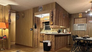 A kitchen with wooden paneling, a bar area, and a dining table with chairs.