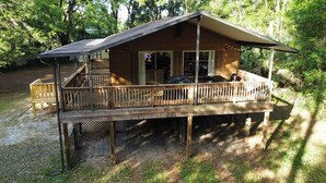 A wooden cabin with a deck, a covered porch, and a large sliding glass door.